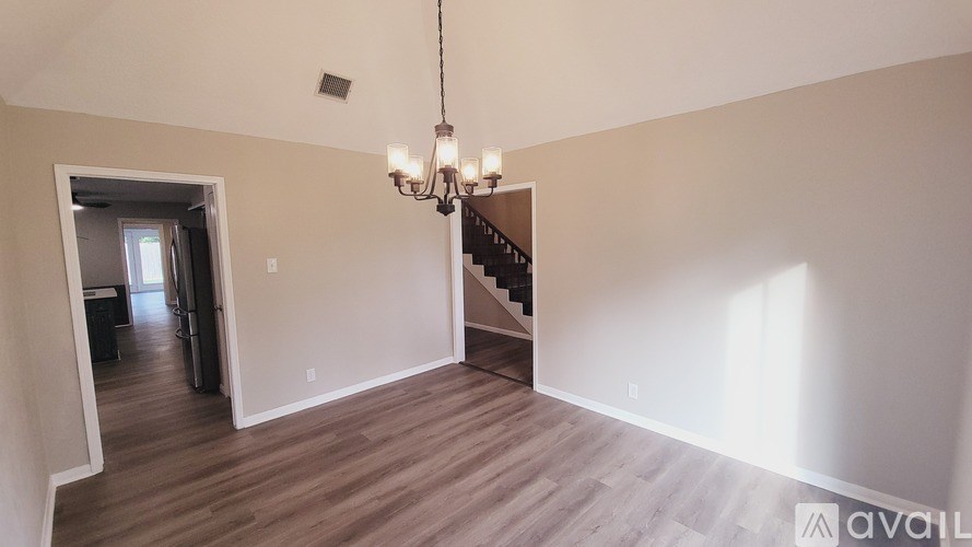 A room with wooden floors and a chandelier hanging from the ceiling.