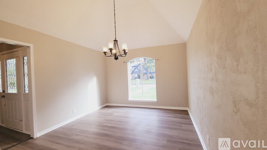A room with wooden floors and a chandelier hanging from the ceiling.