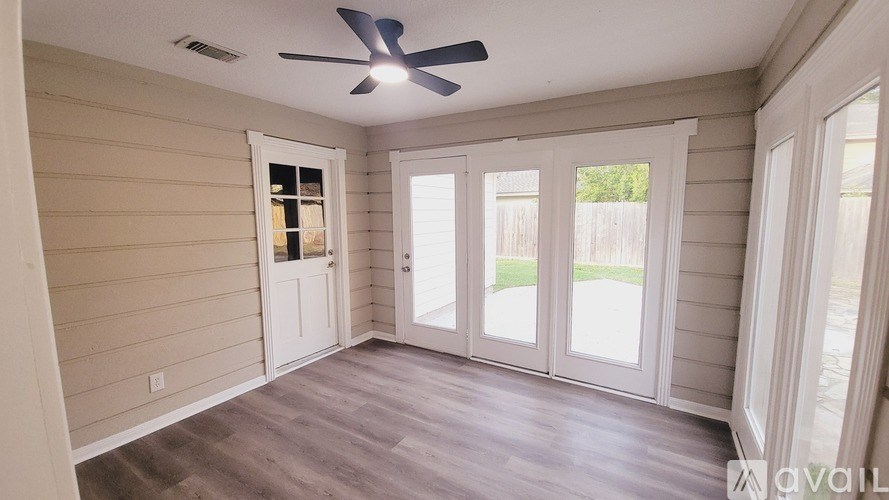 A room with a ceiling fan and sliding glass doors.