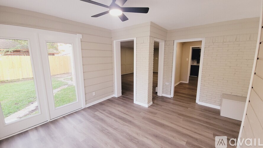 A room with a ceiling fan and sliding glass doors.