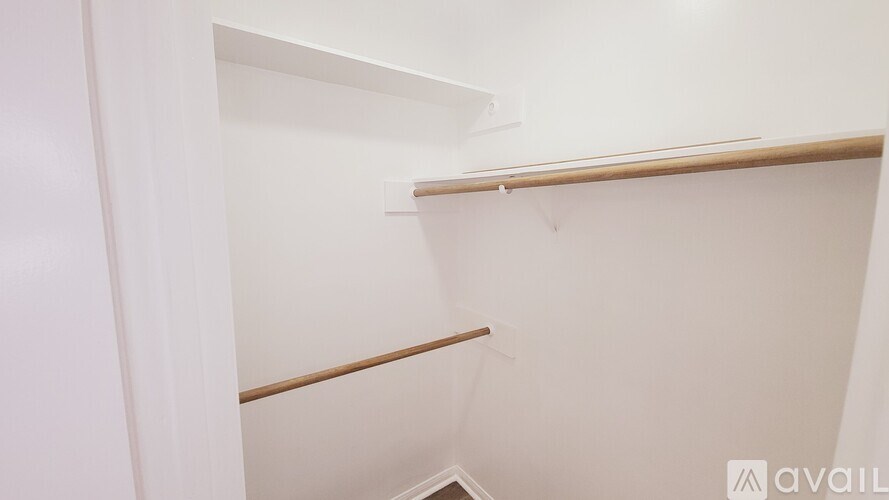 A white closet with a wooden shelf and a white door.