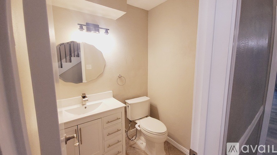 A bathroom with a toilet, sink, and mirror.