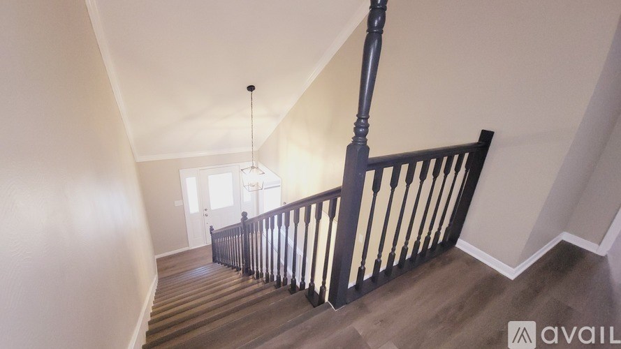 A wooden staircase with a black railing and a light hanging from the ceiling.