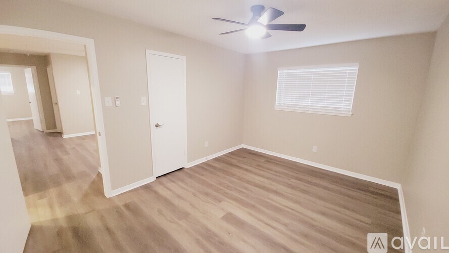 A room with a ceiling fan and wooden flooring.