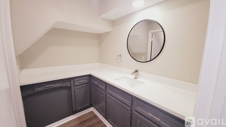 A bathroom with a round mirror and a white sink.