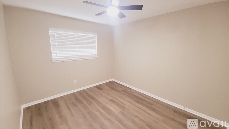 A room with a ceiling fan and a window with blinds.