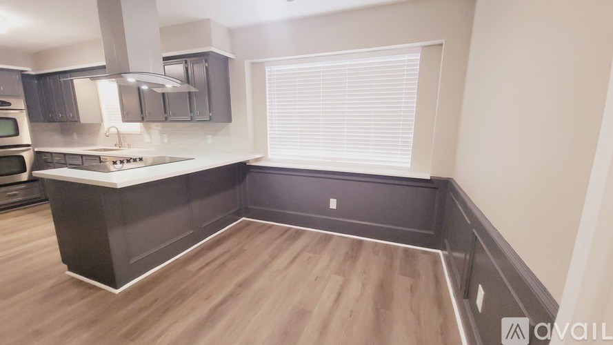A kitchen with a wooden floor and dark brown cabinets.