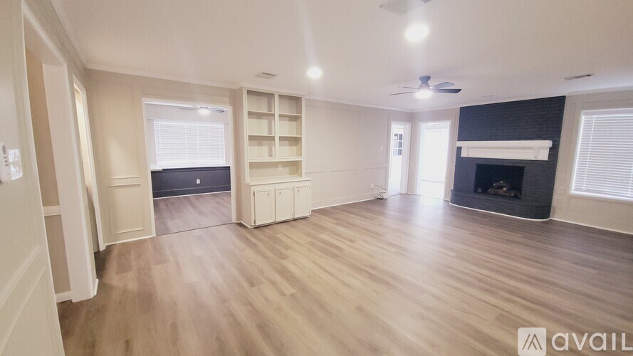 A spacious living room with wooden flooring and a fireplace.