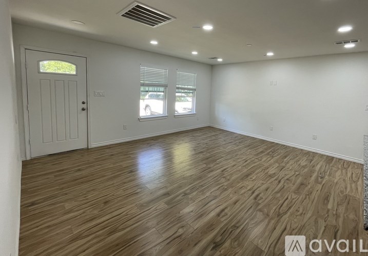 A room with wooden flooring and a door leading to a balcony.