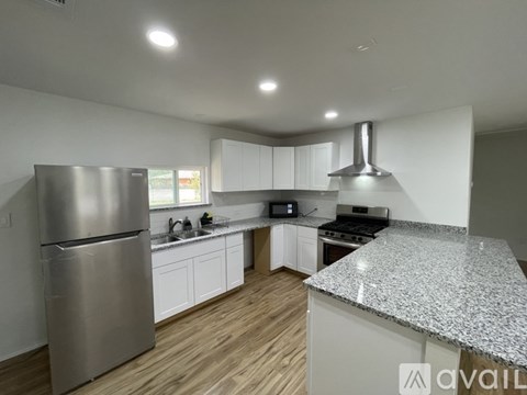 A modern kitchen with a stainless steel refrigerator and a granite countertop.