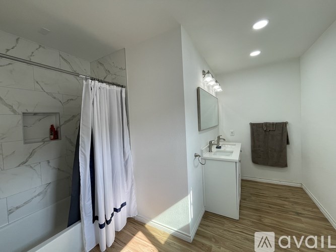 A bathroom with a marble tub surround and a white sink vanity.