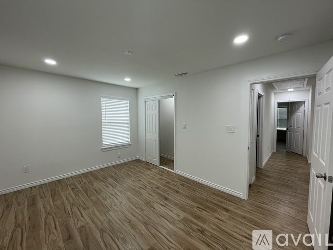 A spacious room with wooden flooring and white walls.