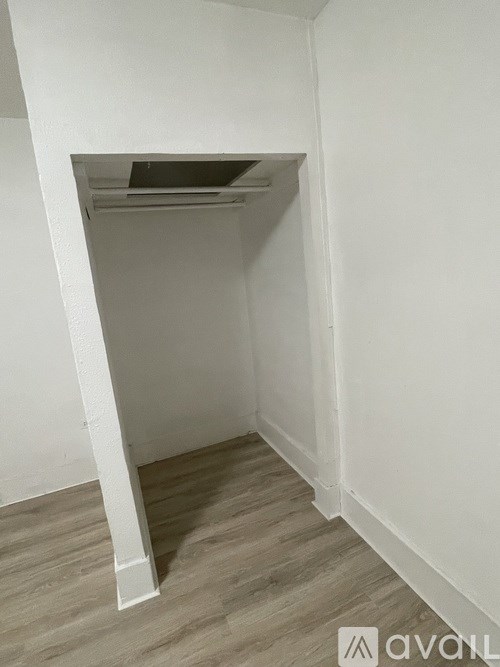 A white room with a wooden floor and a white column.