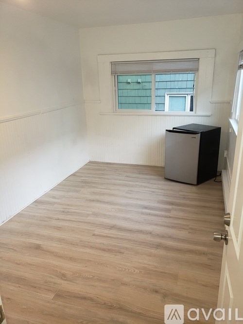 A room with wooden flooring and a window with blinds.