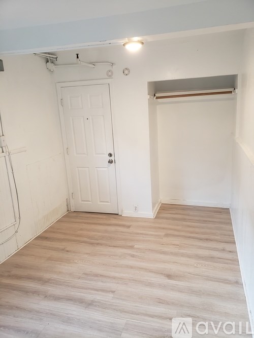 A room with a white door and wooden flooring.