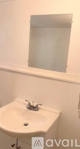 A white sink with a silver faucet and a mirror above it.