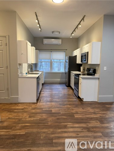 A kitchen with white cabinets and wooden floors.