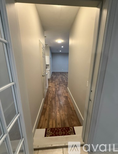 A hallway with a wooden floor and white walls.