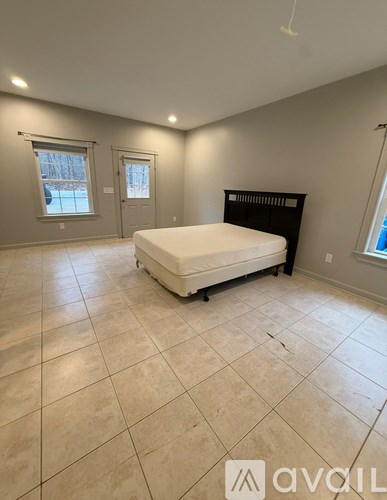 A bedroom with a bed on a white mattress and a black headboard.