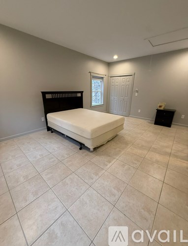 A large, empty room with a bed and a cabinet.