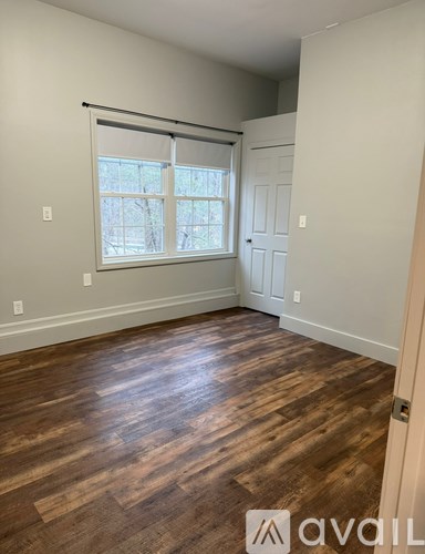 A room with wooden flooring and a window with blinds.