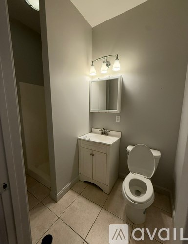 A small white bathroom with a toilet, sink, and mirror.