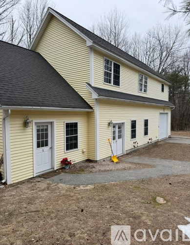 A yellow house with a black roof and a white door.