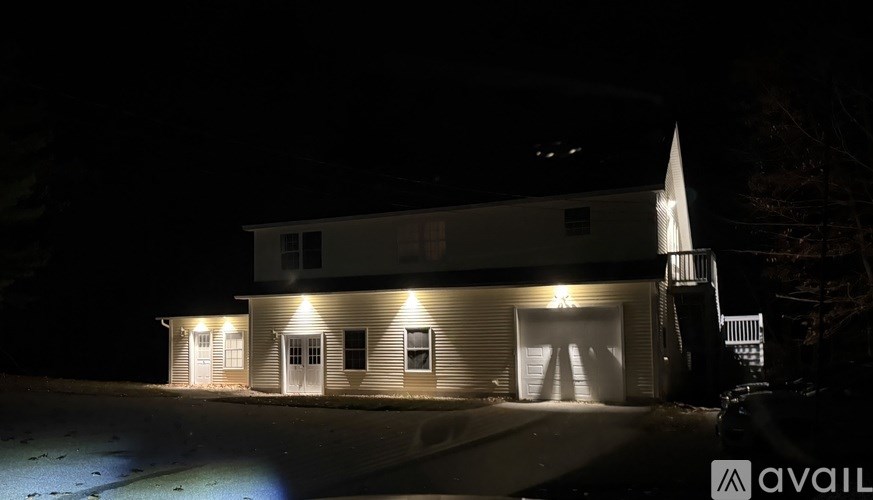 A house is lit up at night with a sign that says "available" in the foreground.