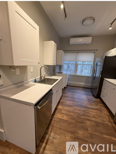 A kitchen with white cabinets and a wooden floor.
