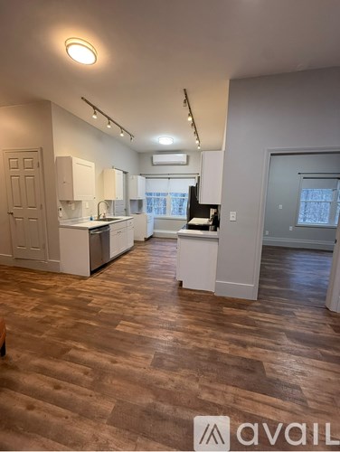 A kitchen with white cabinets and a wooden floor.