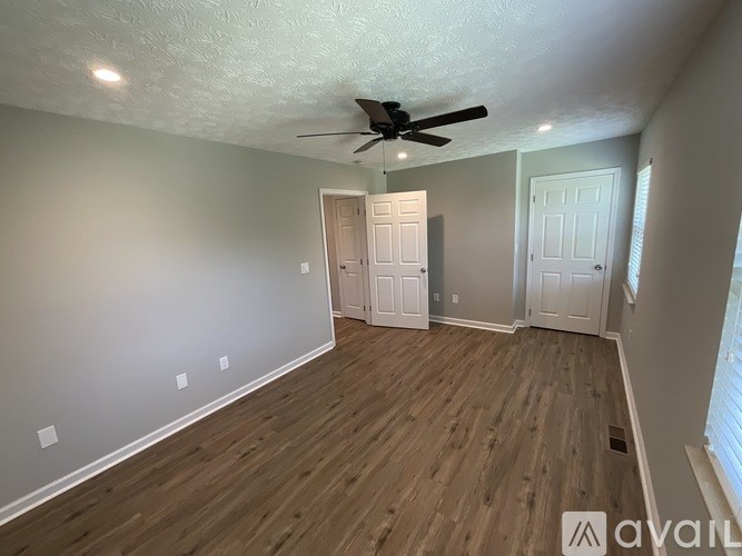 A room with a ceiling fan and wooden flooring.
