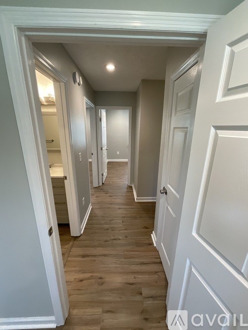 A hallway with white doors and wooden floors.