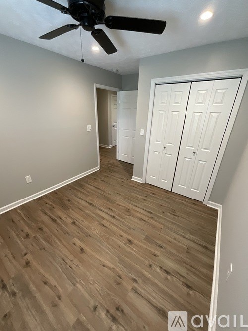 A room with a ceiling fan and wooden flooring.
