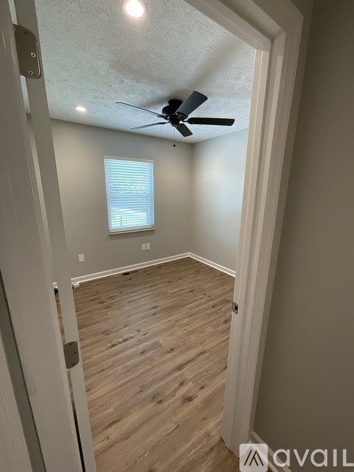 A room with a ceiling fan and wooden flooring.