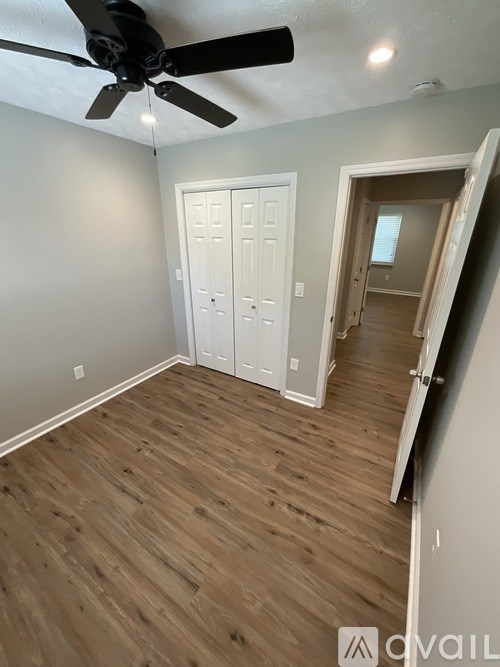 A room with a ceiling fan and wooden flooring.