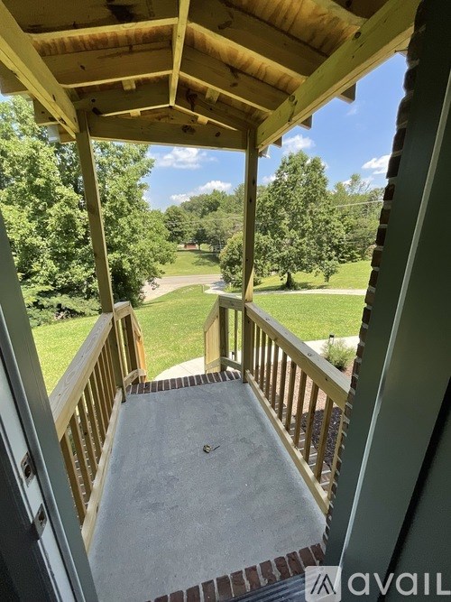 A wooden deck with a view of a green lawn and trees.