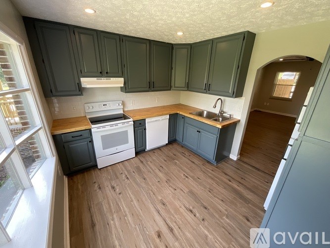 A kitchen with dark green cabinets and a white stove top oven.