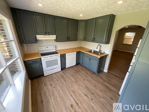 A kitchen with dark green cabinets and a white stove top oven.
