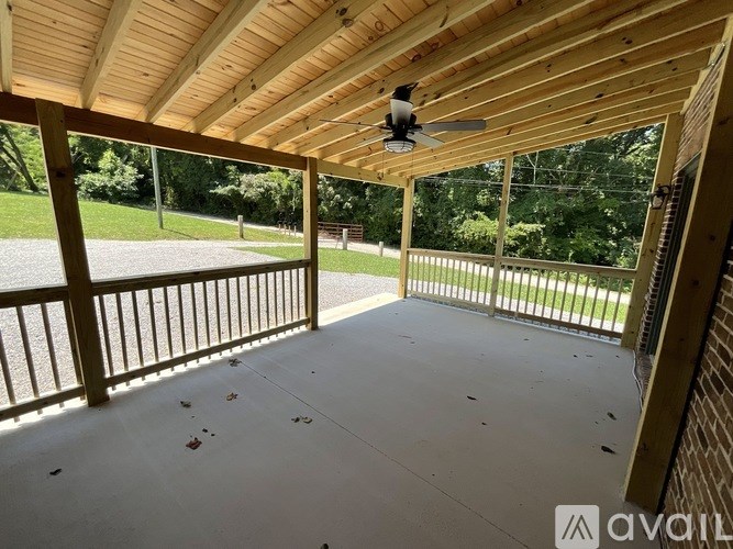 A wooden covered patio with a ceiling fan and sliding glass doors.
