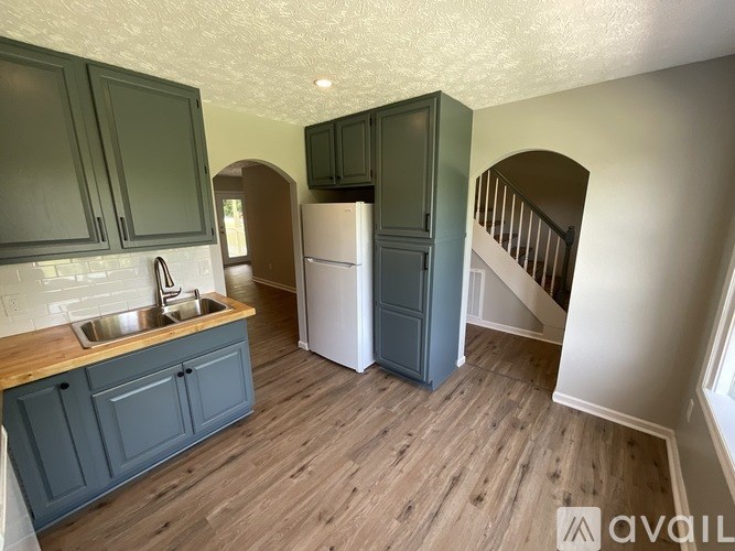 A kitchen with dark green cabinets and a white refrigerator.