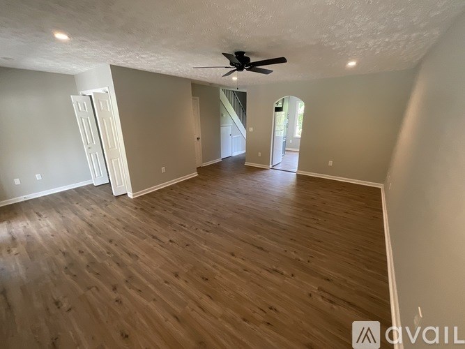 A spacious room with wooden flooring and a ceiling fan.
