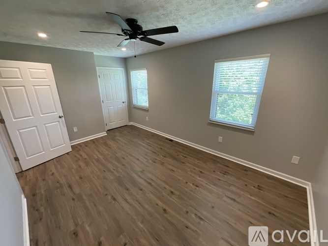 A room with a ceiling fan and wooden flooring.