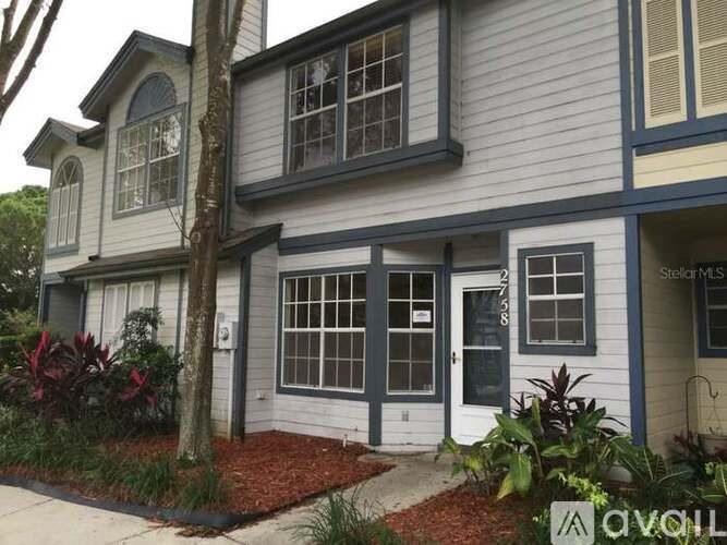 A house with a grey and white exterior and a red brick walkway.