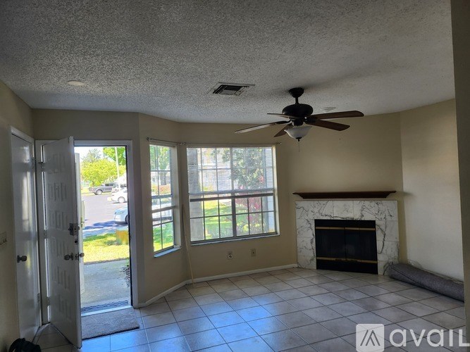 A living room with a fireplace and a ceiling fan.