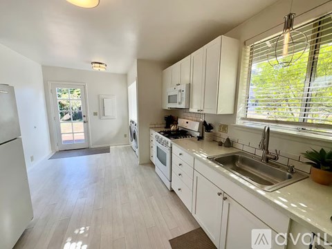 A kitchen with white cabinets and appliances.