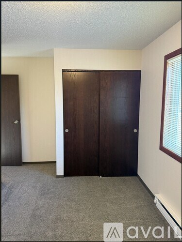 A room with a brown door and a grey carpet.