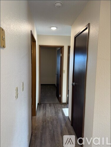 A hallway with a door on the right and a light switch on the wall.