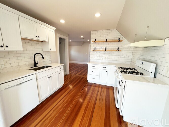 A kitchen with white cabinets and a wooden floor.