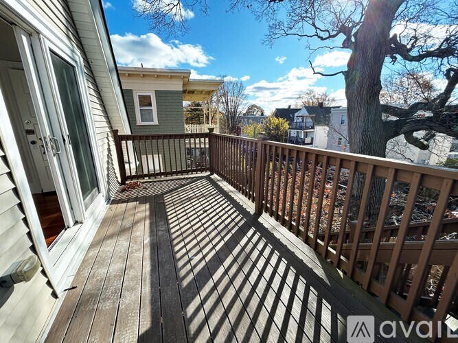 A wooden deck with a railing and a tree in the background.