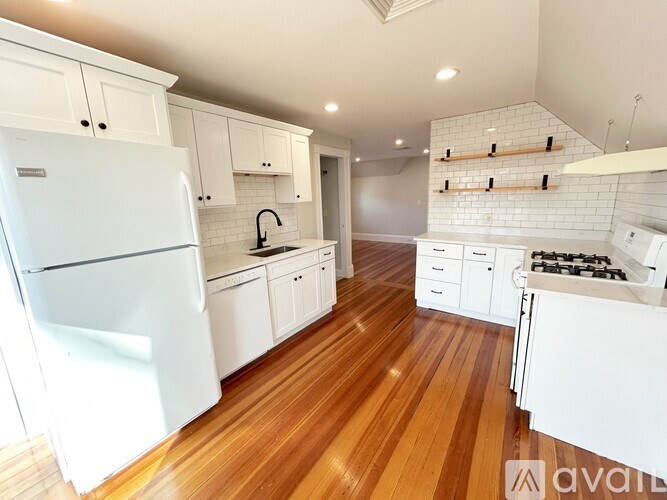 A kitchen with white appliances and wooden floors.